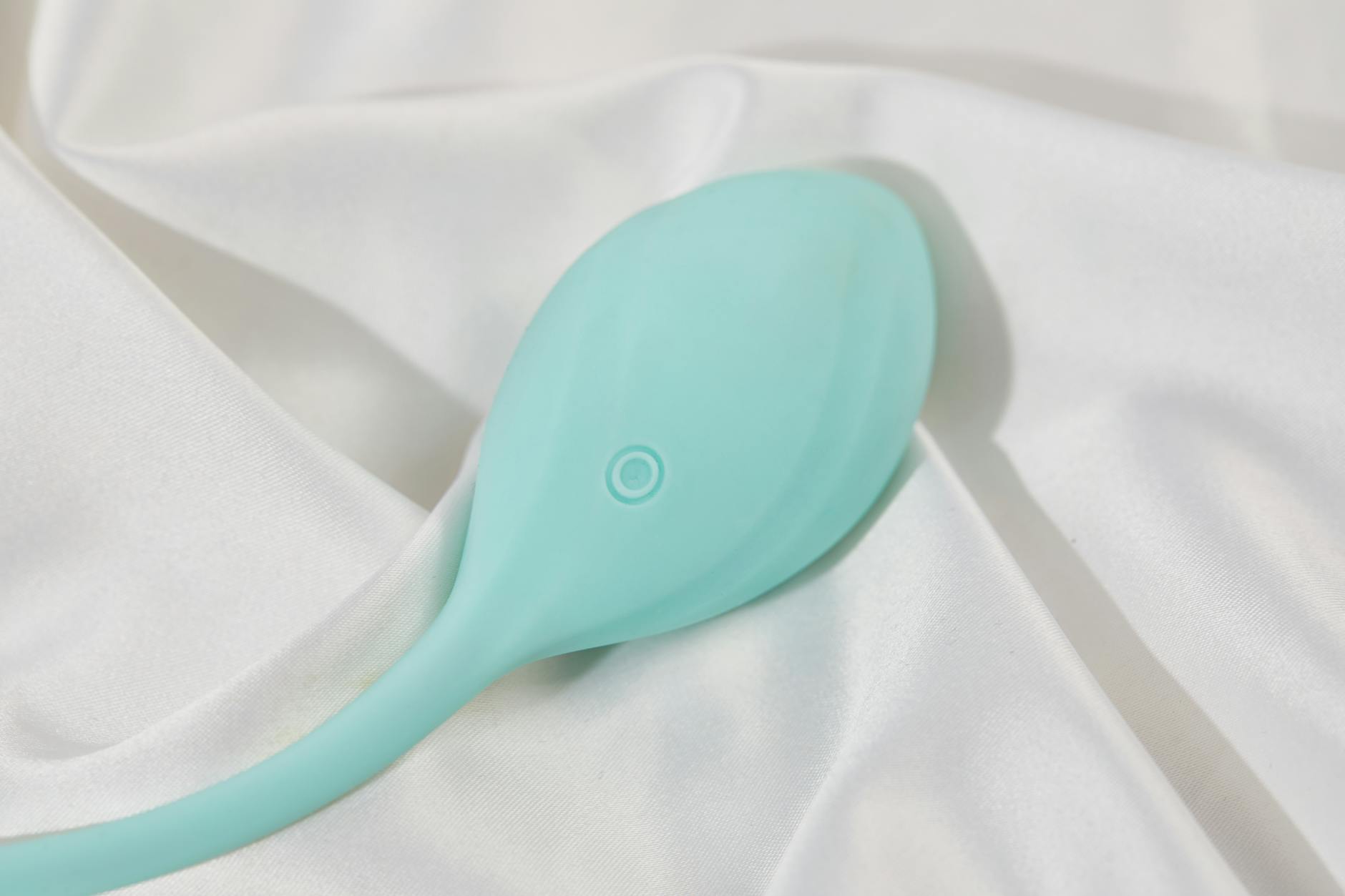 A stylish teal lemon vibrator resting on white silk, symbolizing sensual pleasure recovery