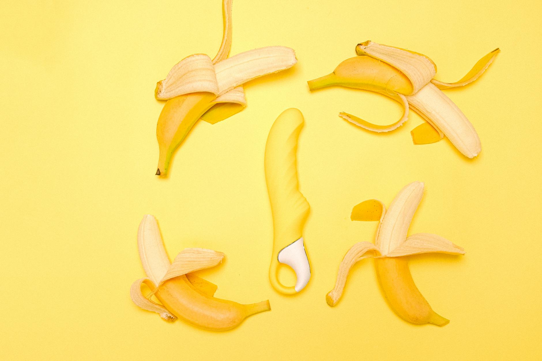 A close-up of a hand holding a lemon vibrator against a minimalistic purple backdrop, showcasing modern sensuality.