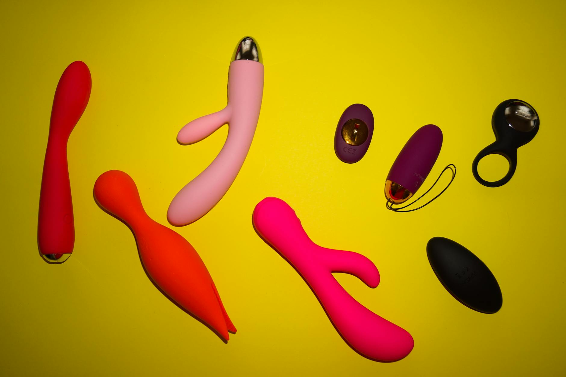 Colorful clitoral vibrators arranged on a bright yellow background, showing design variety