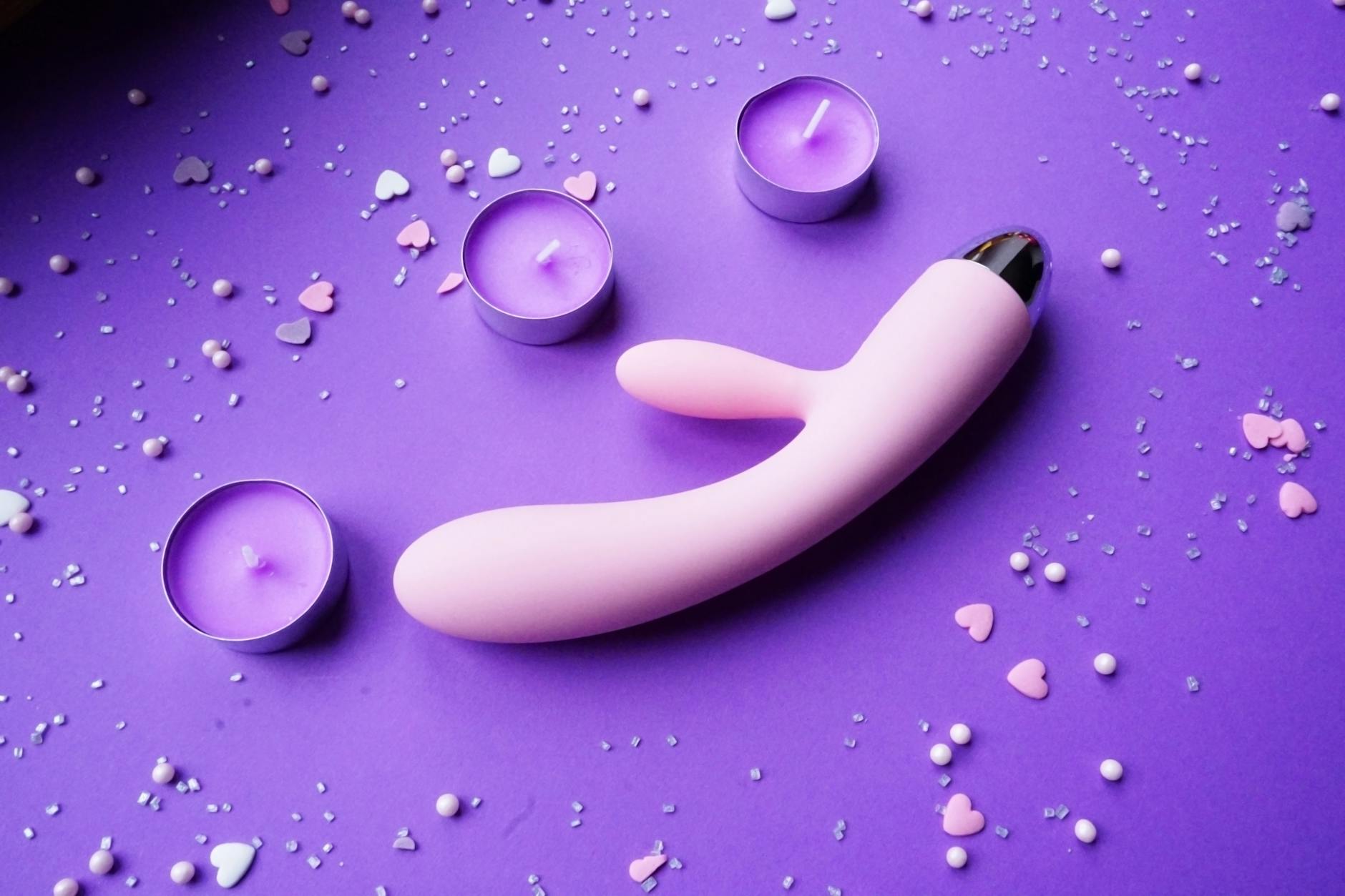 Lemon vibrator and romantic candles on purple background